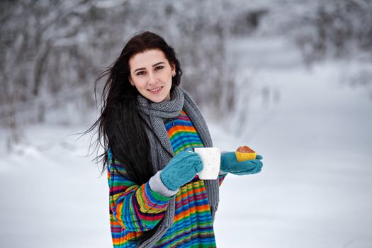 Beautiful young woman in a sweater. Winter outdoors walk with a cup of coffee