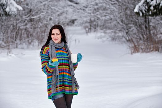 Beautiful young woman in a sweater. Winter outdoors walk with a cup of coffee