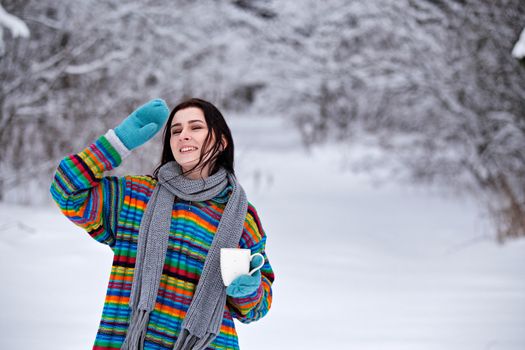 Beautiful young woman in a sweater. Winter outdoors walk with a cup of coffee