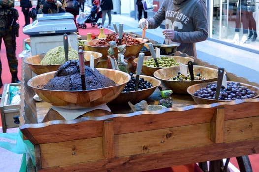 Wooden display case with green and black olives and olive paste