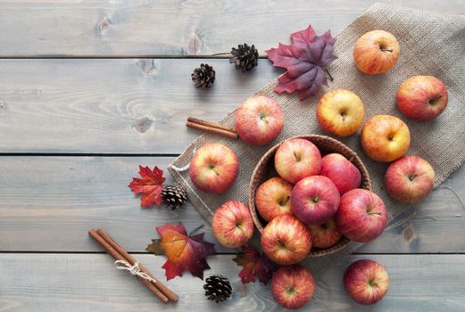 Autumn leaves with apples over a wooden background