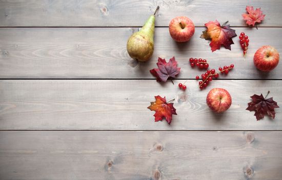 Autumn leafs with fruits over a wooden background