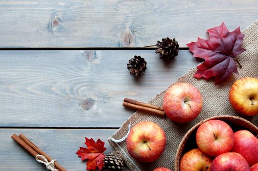 Autumn leaves with apples over a wooden background