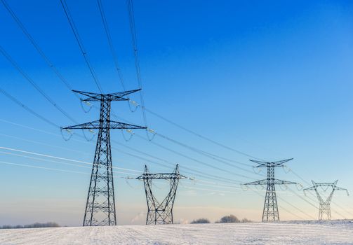 power lines in a snowy landscape on blue sky