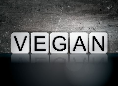 The word "Vegan" written in white tiles against a dark vintage grunge background.