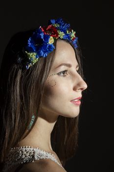 Portrait of a girl in a wreath of flowers on a dark background