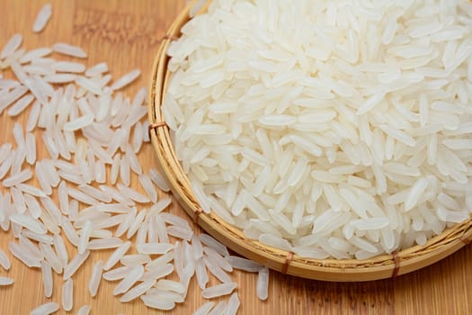 Closeup of Thai jasmine rice in bamboo basket and on wooden table