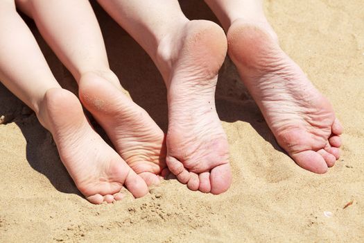 Feet of mother and her child in the sand