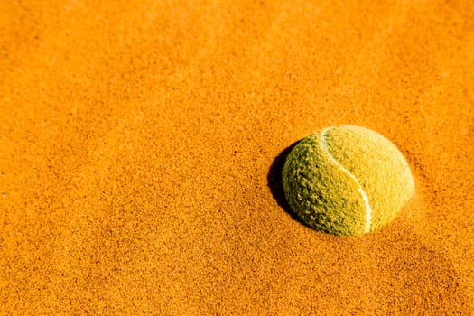 Tennis ball inserted into the sand. Concept, Metaphor