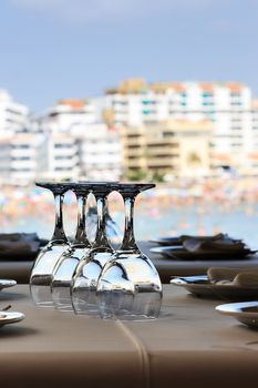 Restaurant on the seashore with the table set. Crystal glasses close up. Vertical image.