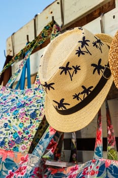 Straw hat with drawings of palm trees in a summer market. Vertical image.