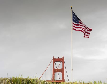 pillar of the Golden Gate Bridge with American flag and grass