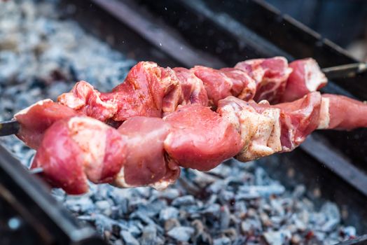 raw meat on skewers cooked on fire