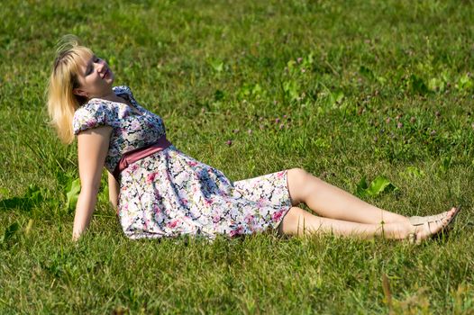 Pregnant woman sunbathing on lawn in the Park