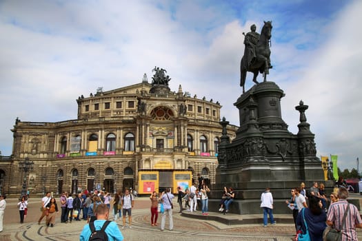 DRESDEN, GERMANY – AUGUST 13, 2016: Tourists walk and visit on Semperoper opera (Staatskapelle Dresden) at Theaterplatz, building was designed by Gottfried Semper in Dresden, Germany on August 13, 2016.