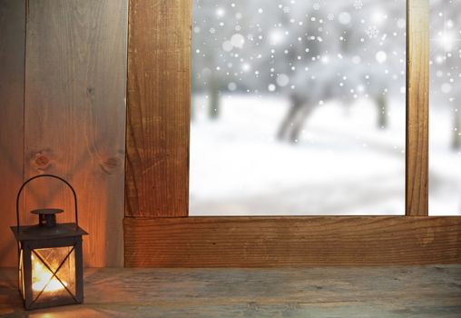 Lantern next to a window with wintery scenery outdoors 