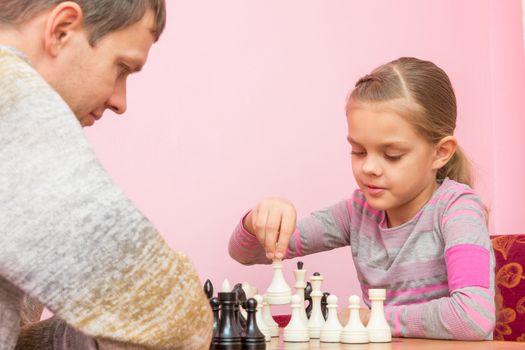 Girl makes the next move while playing chess with the coach