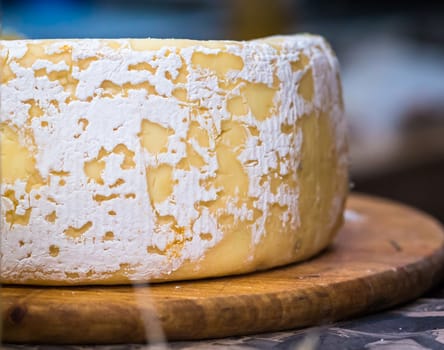 a piece of hard cheese on a wooden board. Big and delicious