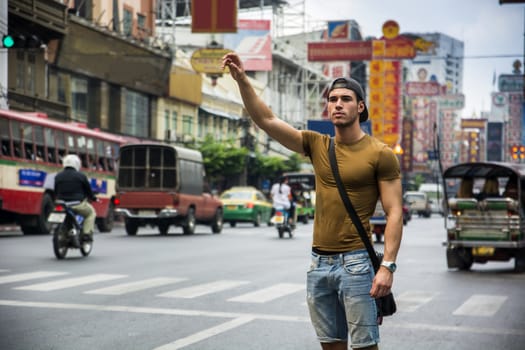 Man standing in the street with hand up in Bangkok, Thailand. Horizontal outdoors shot