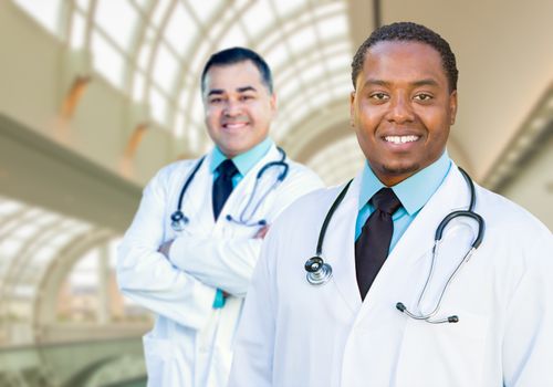 African American and Caucasian Male Doctors Inside Hospital Office.