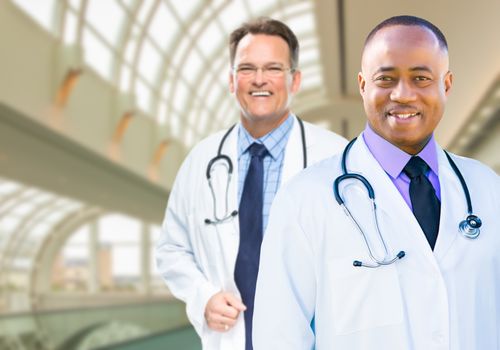 African American and Caucasian Male Doctors Inside Hospital Office.