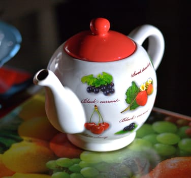 White tea pot with fruit on black background