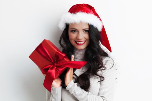 Young happy woman in santa hat holding christmas gift box