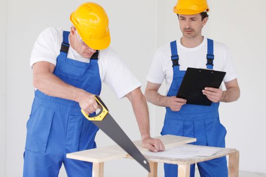 Male worker sawing a wooden board at work