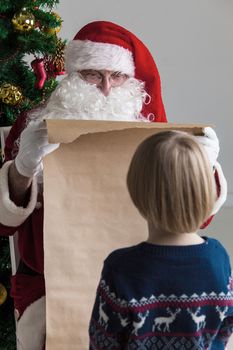 Santa Claus holding list on old paper and child choosing gift