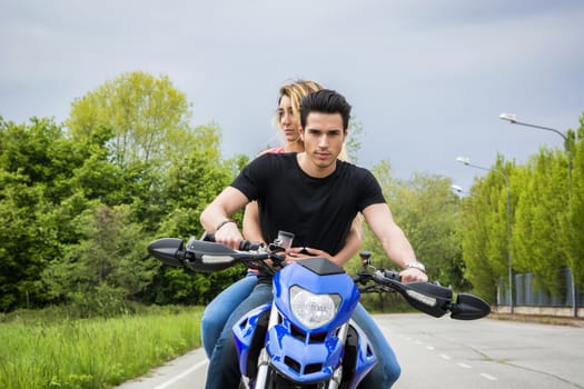 Handsome young man riding motorcycle with woman as passenger