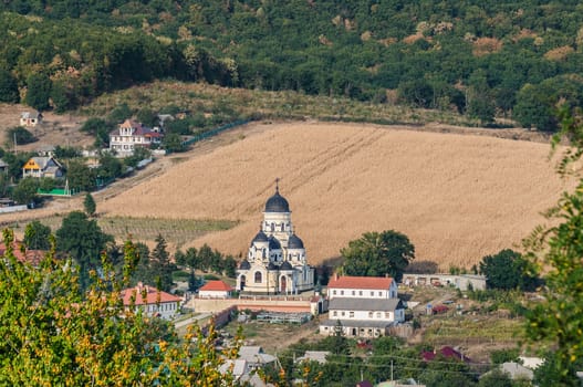 Landscape view with Capriana Monastery and the village around. Winter Church visible at center was built in Neo-Byzantine style in 1903. Capriana Orthodox Christian Monastery is one of the oldest monasteries of Moldova, first time mentioned in 1429.