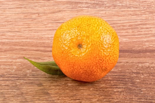 Mandarin with leafs over brown wooden background