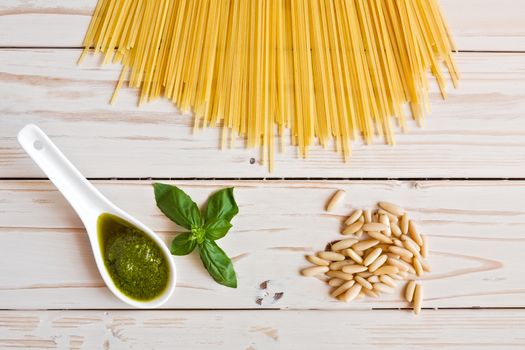 Pesto genovese sauce and linguine pasta, pine nuts and garlic on a table seen from above
