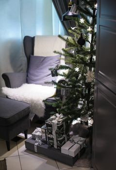 Christmas tree and a soft Chair in the room.