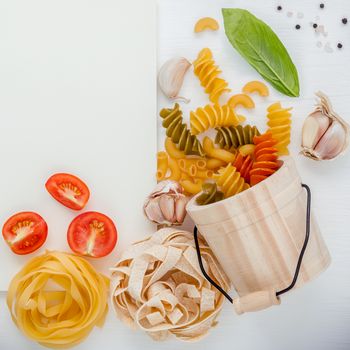 Italian foods concept and menu design . Various pasta elbow macaroni ,fusilli ,fettucini with ingredients sweet basil ,pepper,tomato and garlic setup on white background  flat lay and copy space .