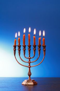 Traditional jewish menorah with lighting candles on nice blue background