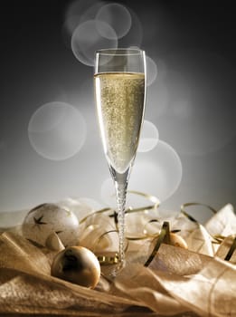 One champagne glass and decoration on golden and silver background