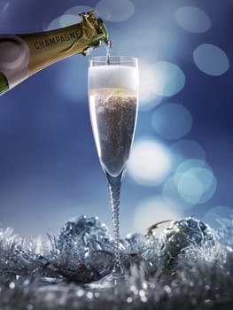 flute of champagbe with golden bubbles on dark blue light bokeh background