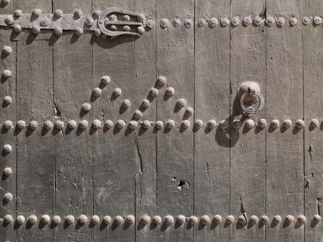 Fragment of old wooden door with rusty handle and big iron nails
