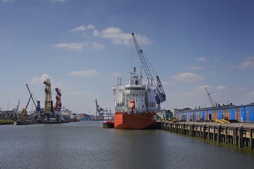 industrial ship with a life boat at a sunny day get unloaded in the port of rotterdam