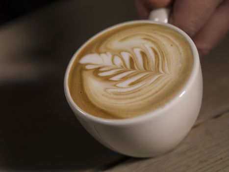 Making latte Art on a Cappucinno on a dark wooden background