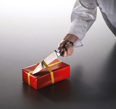 A man opens a birthday or Christmas present with a knife.