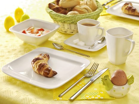 Breakfast table with croissant, eggs, olives, fruit and pastries