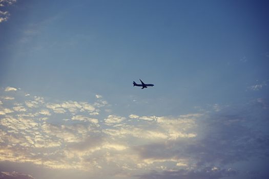 Passenger airplane in blue cloudy sky long away