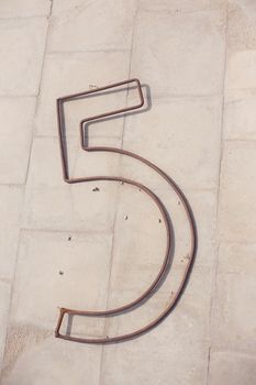 Number five metal figure of wire on floor