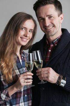 Happy couple in casual clothes clinking champagne celebrating new year