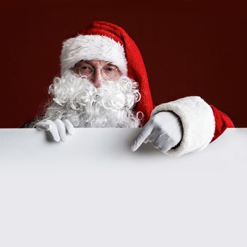 Santa Claus pointing at copy space at big blank card