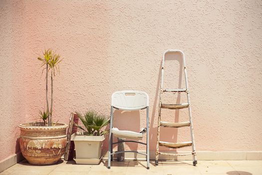 Mainstream fashion photo. Objects standing in a row stepladder chair pot on wall background