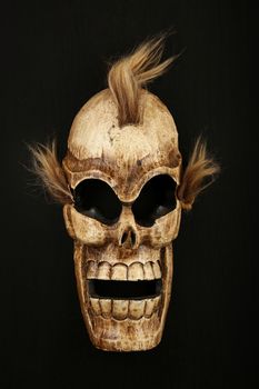 Handmade wooden carved creepy skull death joker mask on black background close up