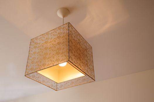 beautiful chandelier in the bedroom with beige ceiling, close-up